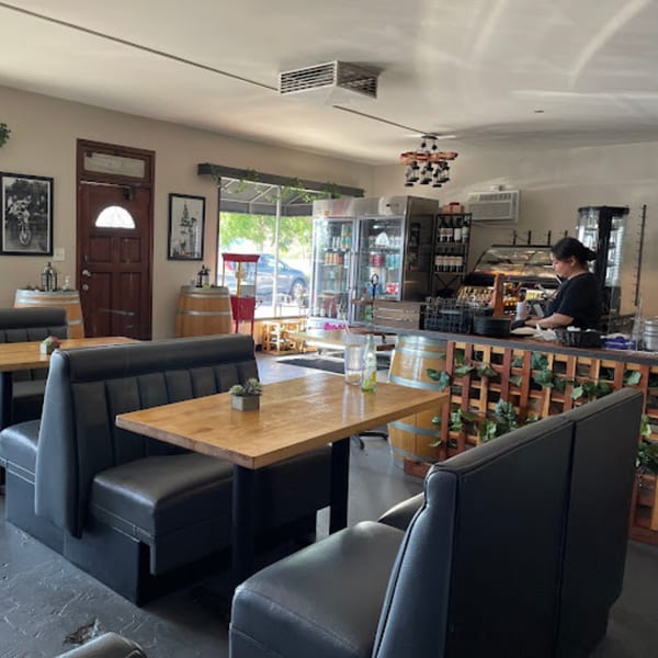 Interior of Lord Empanada with black booths, wooden tables, and a server behind the counter.