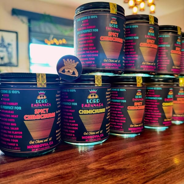 Lord Empanada's Spicy Chimichurri jars are stacked on a wooden counter, ready for purchase.
